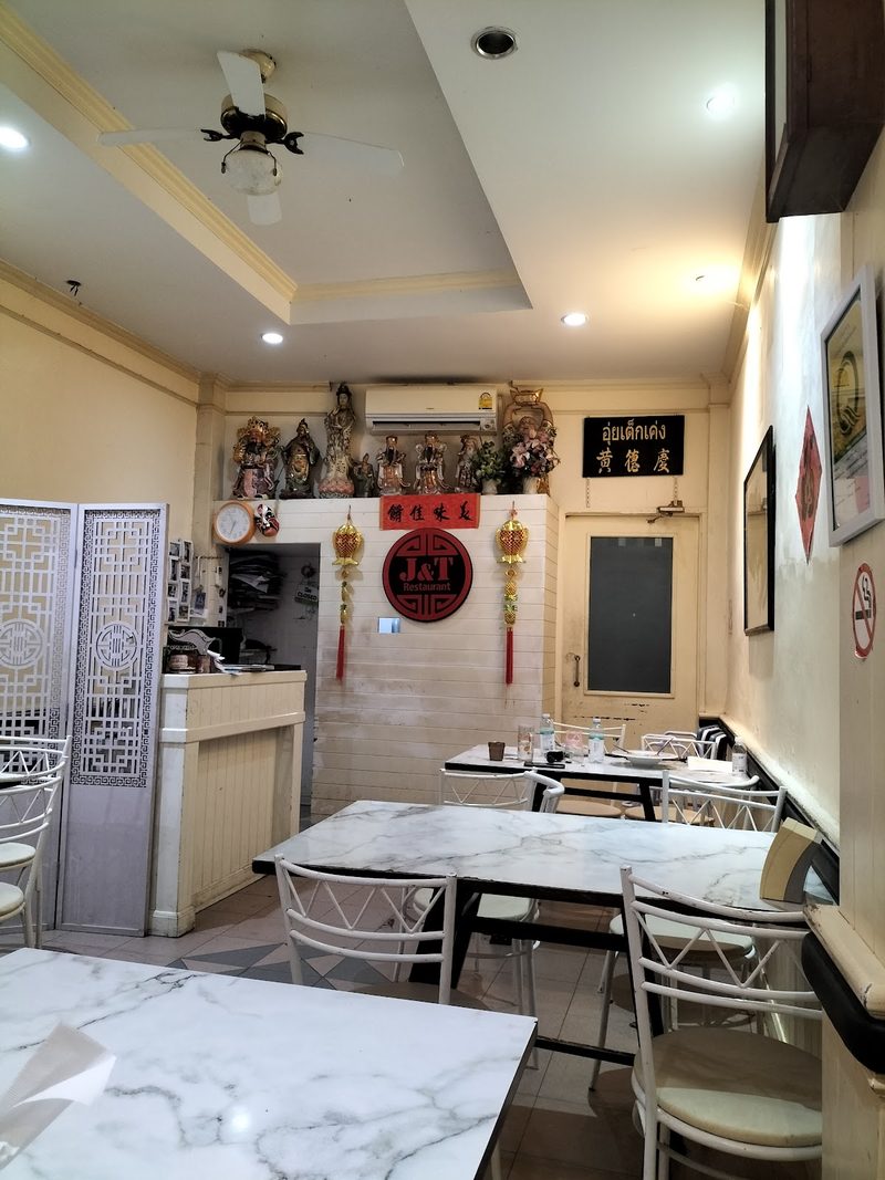 ห้องอาหารโต๊ะหินอ่อน เก้าอี้ขาว ผนังประดับรูปเทพเจ้าจีนและป้ายมงคล