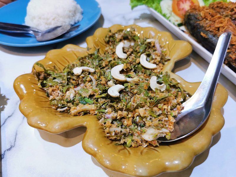 ยำยอดกาหยูโรยเม็ดมะม่วงหิมพานต์ในจานรูปใบไม้