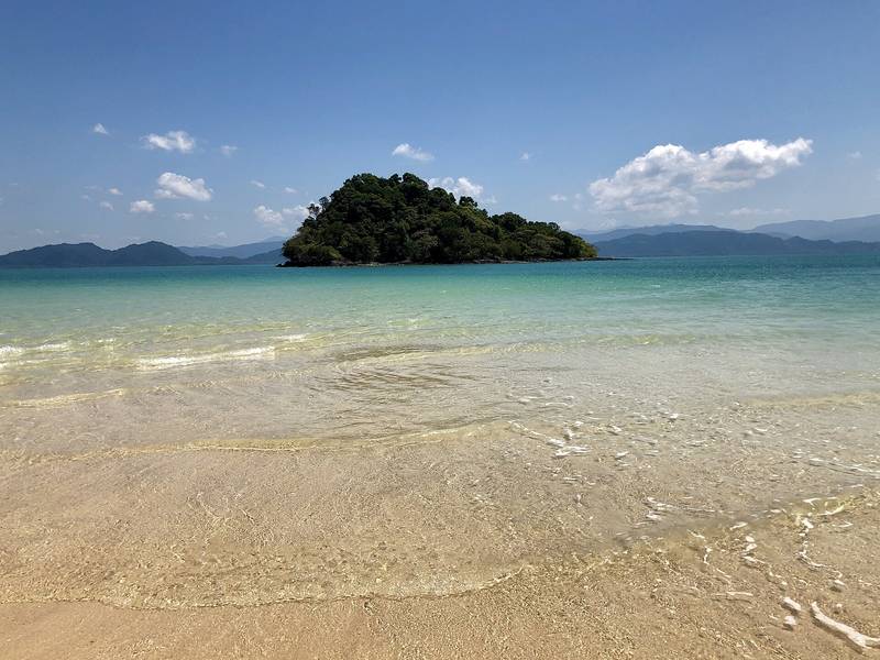 หาดทรายน้ำใสตื้น มีเกาะเล็กอยู่กลางทะเลและแนวภูเขาไกล ๆ